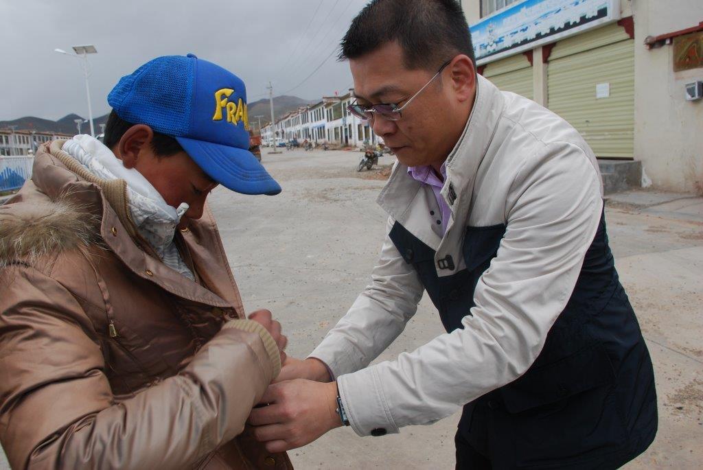 2015年7月，金利来集团主席曾智明在西藏为孩子穿上金利来冬衣